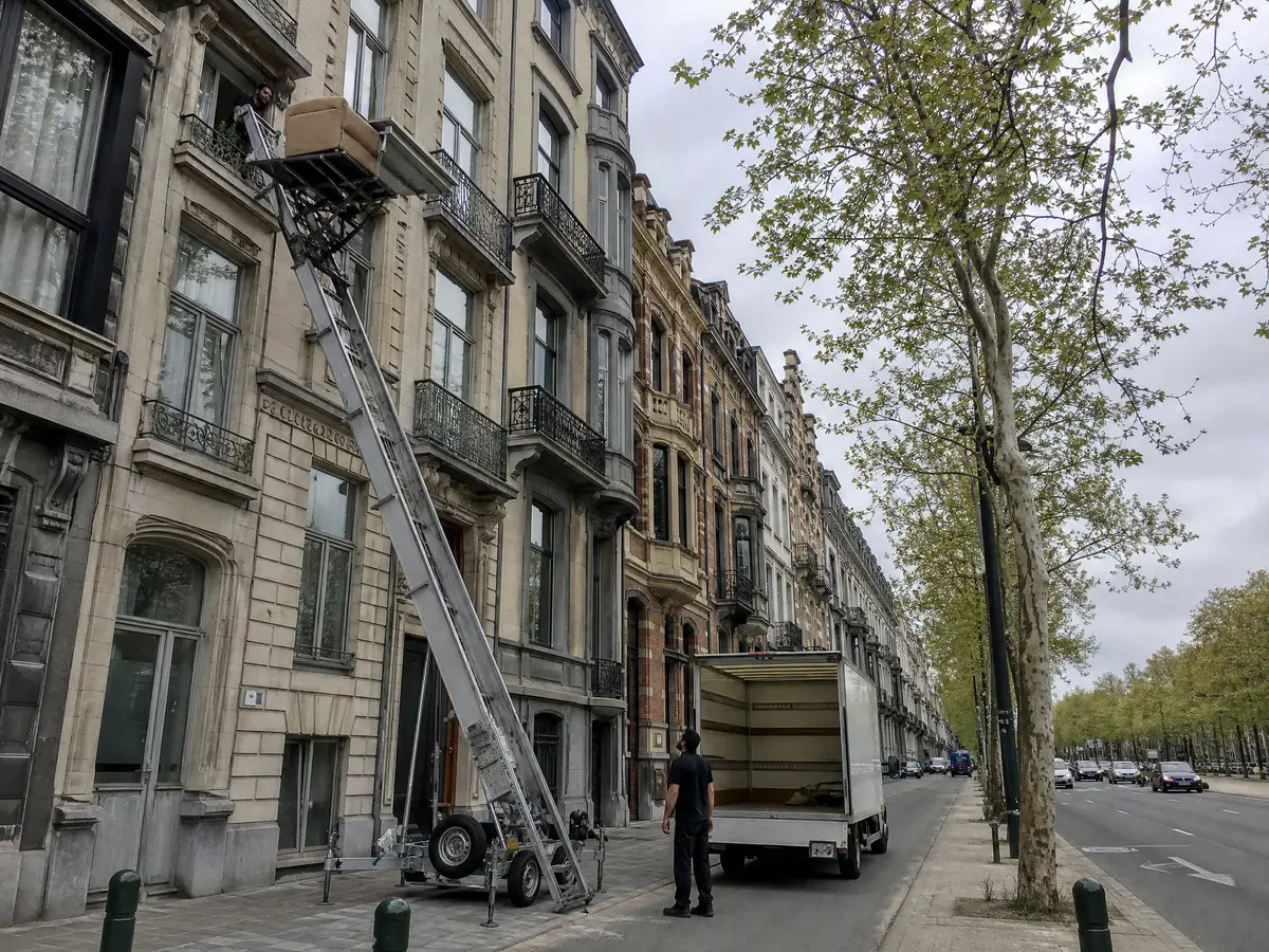 Ladder lift brings an armchair down from a fifth-floor window of an apartment building on the Antwerpen Leien
