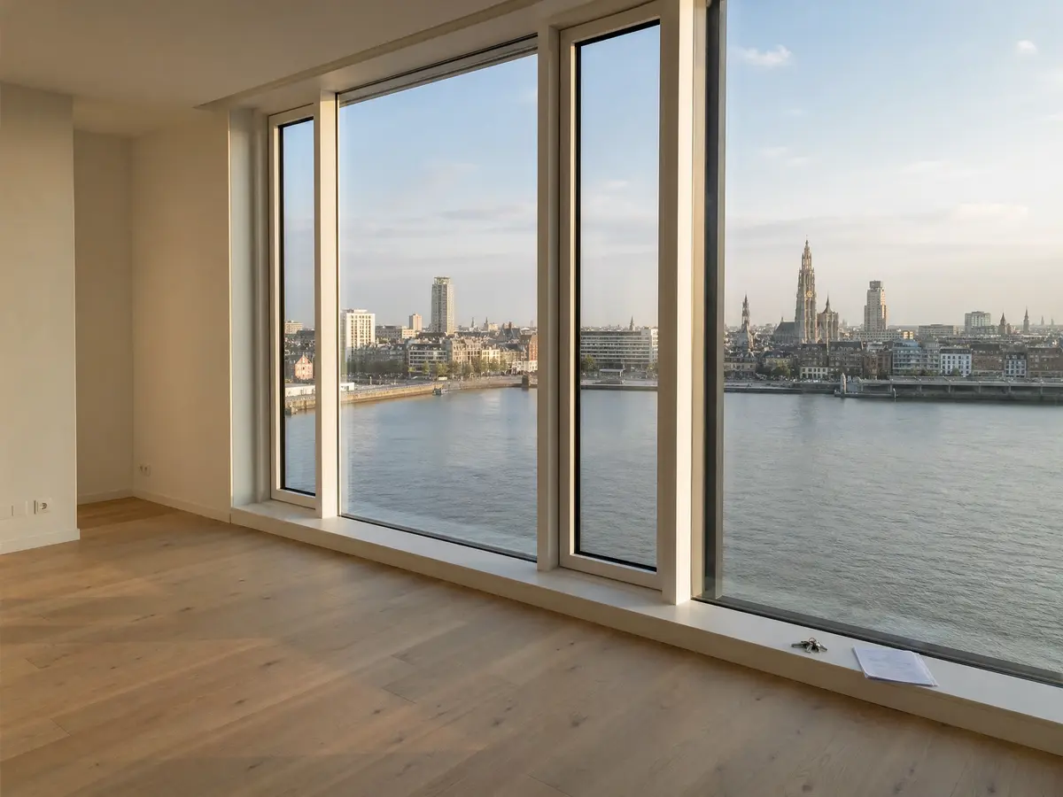 Empty swept apartment on Antwerpen's Left Bank with keys on the window sill and the skyline across the Scheldt