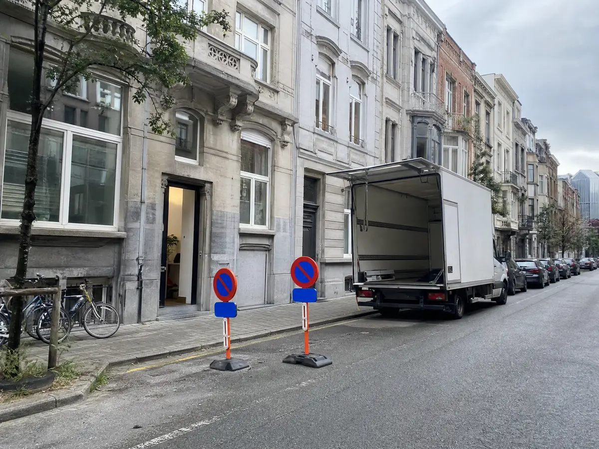 Temporary no-parking signs keep a loading space free in front of an Antwerpen row house before a clearance